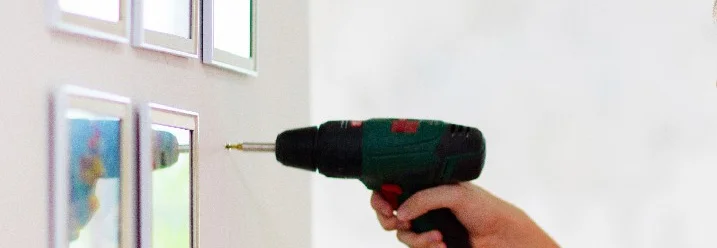 Person bringt mit Akkuschrauber Bilder an